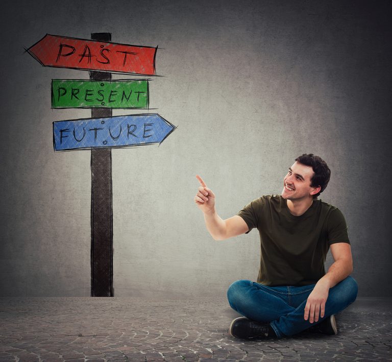 Young Man Sitting On The Floor Pointing Forefinger At Signpost A T